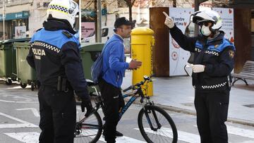 Dos policías señalan a una persona que va subido en una bicicleta que no puede estar en la calle.