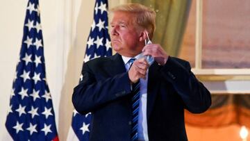 FILE PHOTO: President Donald Trump pulls off his protective face mask as he poses atop the Truman Balcony of the White House after returning from being hospitalized at Walter Reed Medical Center, October 5, 2020.  REUTERS/Erin Scott/File Photo