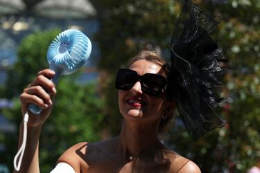 Una mujer se refresca con un ventilador portátil a su llegada al hipódromo de Ascot.