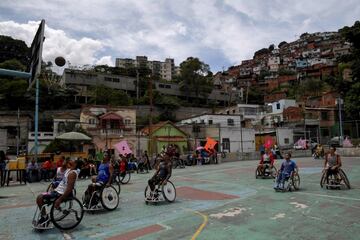 Un grupo de personas en silla de ruedas juegan al baloncesto en una cancha situada en el barrio de Artigas, en Caracas (Venezuela). Los vecinos organizaron este encuentro para ayudarlos a luchar contra la precariedad existente en uno de los barrios más castigados por la profunda crisis que azota al país sudamericano.