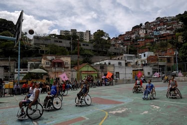 Un grupo de personas en silla de ruedas juegan al baloncesto en una cancha situada en el barrio de Artigas, en Caracas (Venezuela). Los vecinos organizaron este encuentro para ayudarlos a luchar contra la precariedad existente en uno de los barrios más castigados por la profunda crisis que azota al país sudamericano.