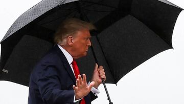 U.S. President Donald Trump walks without a mask and carries an umbrella while boarding Air Force One as he departs Washington for travel to Florida, his first campaign trip since being treated for the coronavirus disease (COVID-19), at Joint Base Andrews, Maryland, U.S., October 12, 2020. REUTERS/Jonathan Ernst
