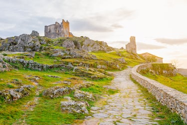 Trevejo, una pequeña pedanía de la comarca de la Sierra de Gata en Cáceres, es un pueblo de gran valor histórico y paisajístico que parece suspendido en el tiempo. Su rasgo más característico es su imponente castillo medieval, cuyas ruinas de pizarra y granito se alzan sobre un peñasco, dominando visualmente el valle. Este fortín templario, testigo de un pasado de batallas y órdenes militares, es el alma del pueblo y ofrece unas vistas panorámicas espectaculares. Las pocas casas del núcleo urbano, construidas con la arquitectura tradicional de la sierra, están diseminadas en las faldas de la colina y dan al lugar un ambiente de tranquilidad y autenticidad. La visita a Trevejo es un viaje a la historia y un encuentro con la naturaleza más virgen de la zona.
