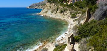 Esta cala cuenta con 40 metros de longitud y apenas 5 metros de anchura. Con cantos rodados y aguas muy tranquilas donde abunda vegetación de posidonia. Un entorno muy atractivo gracias a la vista de los coloridos edificios del arquitecto Ricardo Bofill con concepción geométrica. 