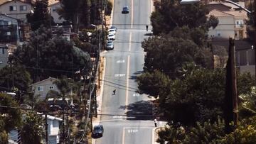 Milton Martínez realizando hillbomb en skate en las colinas de San Diego (California, Estados Unidos) con un coche detrás.