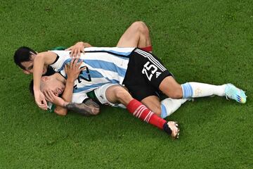 El jugador de México Hirving Lozano se lleva agarrado al suelo al jugador argentino Lisandro Martínez. 
 