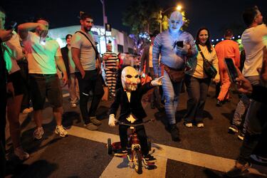 Un niño disfrazado recorre la multitud en triciclo durante el Carnaval de Halloween de West Hollywood, California.