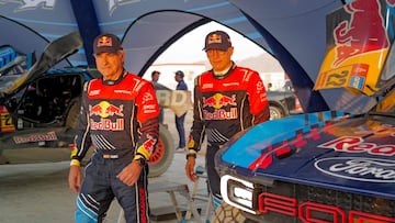 Ford M-Sport's Spanish Driver Carlos Sainz (L) and Spanish co driver Lucas Cruz (R) walk next to their car after a practice session ahead of the start of the Dakar Rally 2025, in Bisha, on January 1, 2025. The Dakar Rally 2025 runs from 3 to 17 January 2025. (Photo by Valery HACHE / AFP)