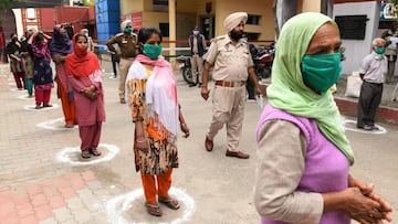 People maintain the recommended distance while waiting to receive free grocery items distributed by police officials during a government-imposed nationwide lockdown as a preventive measure against the COVID-19 novel coronavirus in Amritsar on March 30, 20