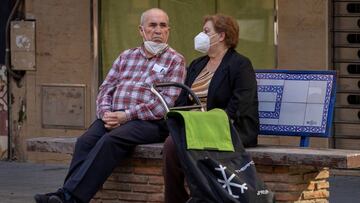 GRAFAND7982. SEVILLA, 02/05/2020.- Una pareja de mayores protegidos con mascarillas descansando hoy en un banco en el barrio de Triana de Sevilla, en el primer día de salida de este colectivo tras 48 días de confinamiento debido al estado de alarma por la pandemia de la COVID-19. EFE/Julio Muñoz