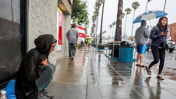 A homeless woman sits along Newport Avenue in the Ocean Beach area of San Diego as Tropical Storm Hilary approaches San Diego, California, U.S., August 20, 2023. REUTERS/Sandy Huffaker