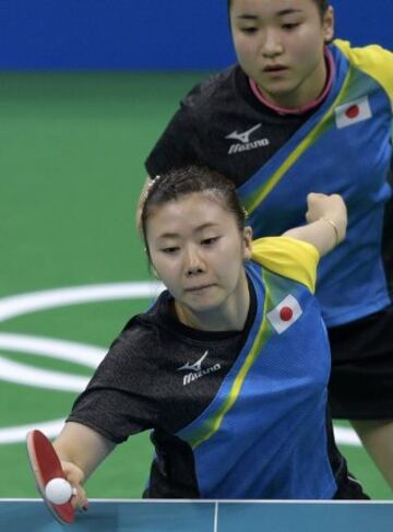 Japan's Ai Fukuhara hits a shot next to Japan's Mima Ito (top) in the women's team quarter-final table tennis match against Austria at the Riocentro venue during the Rio 2016 Olympic Games in Rio de Janeiro on August 13, 2016. / AFP PHOTO / Juan Mabromata