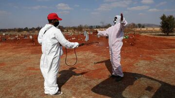 FILE PHOTO: Funeral workers wearing personal protective equipment sanitise each other after a burial amid a nationwide coronavirus disease (COVID-19) lockdown, at the Olifantsvlei cemetery, south-west of Joburg, South Africa July 28, 2020. REUTERS/Siphiwe Sibeko/File Photo