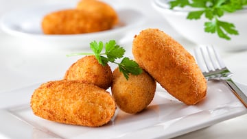 Homemade gourmet croquettes on a white plate with fork.