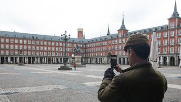 Un hombre hace una foto con su móvil a la céntrica Plaza Mayor de Madrid, vacía durante el estado de alarma decretado por el coronavirus, en Madrid (España)