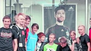 <b>MUY QUERIDO. </b>Un grupo de jóvenes aficionados del Liverpool posan en la tienda oficial de Anfield. La imagen de Xabi Alonso sigue en el escaparate.