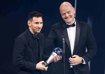 Lionel Messi smiles politely as he accepts his 'The Best' award from FIFA Chief Gianni Infantino.