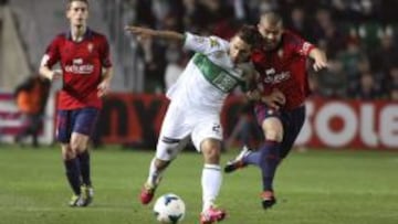 El defensa uruguayo del Elche, Damián Suárez, lucha un balón con el chileno Francisco Silva, de Osasuna, durante el partido, correspondiente a la vigésimo cuarta jornada de Liga en Primera División, que se disputa esta noche en el estadio Martínez Valero, en Elche.