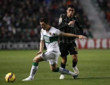 El defensa del Elche Edu Albacar (i) lucha un balón con el delantero portugués del Málaga Ricardo Horta, durante el partido de la decimosexta jornada de Liga de Primera División