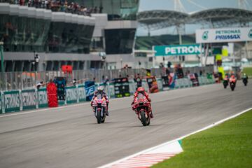 Francesco Bagnaia en la recta principal junto a Enea Bastianini durante la carrera del Gran Premio MotoGP PETRONAS de Malasia en el Circuito de Sepang.