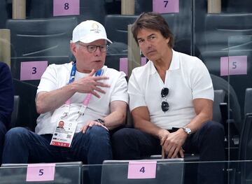 Tom Cruise y el CEO de Warner Bros, David Zaslav, charlan en las gradas mientras esperan la participación de Simone Biles en el concurso de suelo.