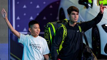 Alcaraz sale a la pista con su raquetero a la espalda.