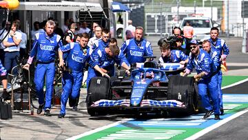 Los mecánicos de Alpine empujan el coche de Alonso en el pit-lane de Austria.