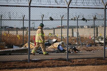 Un rescatista camina junto a los restos de un avión que se estrelló después de salirse de la pista en el Aeropuerto Internacional de Muan.