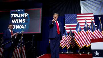 Republican presidential candidate and former U.S. President Donald Trump gestures as his son Eric Trump applauds next to him during his Iowa caucus night watch party in Des Moines, Iowa, U.S., January 15, 2024.  REUTERS/Evelyn Hockstein