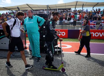 Lewis Hamilton llega a la parrilla antes de la carrera en patinete.