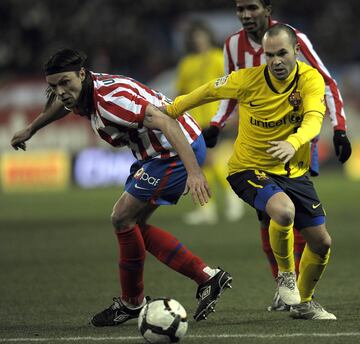 El jugador del Barcelona Iniesta trata de llevarse el bal¨®n ante el jugador del Atl¨¦tico Ujfalusi.