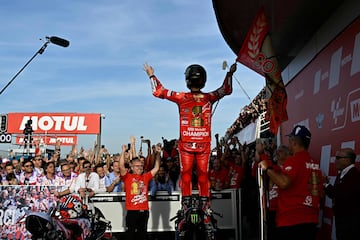 El piloto italiano de Ducati, Francesco Bagnaia, celebra el Mundial encima de su moto y dirigiéndose a su equipo.  