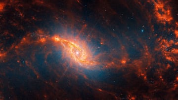 This spiral galaxy was observed as part of the Physics at High Angular resolution in Nearby GalaxieS (PHANGS) program, a large project that includes observations from several space- and ground-based telescopes of many galaxies to help researchers study all phases of the star formation cycle, from the formation of stars within dusty gas clouds to the energy released in the process that creates the intricate structures revealed by Webb’s new images. NGC 1365 is 56 million light-years away in the constellation Fornax. Learn more about what can be seen in this vast collection of Webb images here. [Image description: Webb’s image of galaxy NGC 1365 shows a central region that looks like an angled, smashed oval that is a mix of bright orange shades that emanate a blue glow. The galaxy’s bar extends horizontally from the oval. It is crossed by messy dust filaments that curve slightly, forming a backward S shape. Fainter filaments appear below and above the core.]