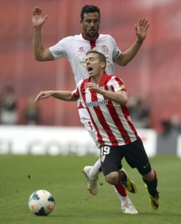 El delantero del Athletic Club Iker Muniain cae ante el centrocampista del Sevilla Vicente Iborra (detrás), en partido de la jornada trigésima quinta de liga en Primera División que se disputa en el estadio San Mamés.