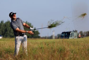 El sudafricano Dean Burmester observa el vuelo de su bola tras el segundo golpe en el hoyo inicial del Royal St. Georges en Sandwich, Kent (Inglaterra). El exigente campo que acoge la 149ª edición del British Open no da tregua a los jugadores que si no cogen calle deben lidiar con elementos de la naturaleza al golpear la bola.  