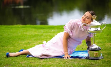 Aryna Sabalenka apoyando su cabeza en el trofeo de campeona del Abierto de Australia en los Jardines Reales de Melbourne.