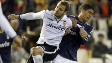 El delantero del Valencia CF, Roberto Soldado (i), salta por el bal&oacute;n con el franc&eacute;s Raphael Varane, del Real Madrid, durante el partido de la vig&eacute;sima jornada de Liga en Primera Divisi&oacute;n que se disputa esta noche en el estadio de Mestalla, en Valencia. 