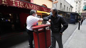 Customers bump elbows at Cafe Tiramisu during the first day of reopening for outdoor dining in San Francisco, California.