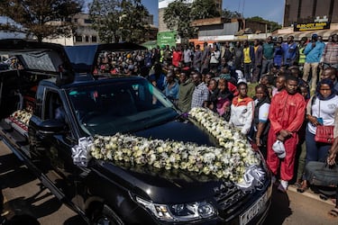 La gente se reúne junto al coche fúnebre que lleva el ataúd del maratonista keniano Kelvin.