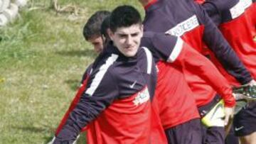 Courtois haciendo estiramientos sobre el césped.