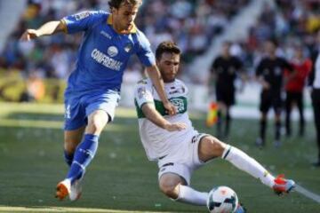 El centrocampista del Getafe Pedro León (i) disputa un balón con el defensa del Elche Domingo Cisma (d).