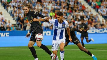 El centrocampista del Leganés Roberto López (c), intenta controlar el balón ante el defensa del Valencia Yarek Gasiorowski (i), durante el encuentro correspondiente a la jornada 9 de Laliga EA Sports que disputan hoy viernes Leganés y Valencia en el estadio de Butarque, en la localidad madrileña.