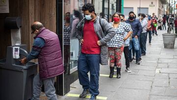 Customers disinfect their hands before entering a store in downtown Lima on July 1, 2020. - Peru began a gradual process of deconfinement on Wednesday to reactivate its semi-paralyzed economy, and the streets of Lima were once again filled with vehicles and people, after three and a half months of mandatory national quarantine due to the COVID-19 coronavirus pandemic. (Photo by ERNESTO BENAVIDES / AFP)