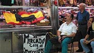 <b>EXPECTACIÓN EN EL MERCADO DE PACÍFICO</b>. Televisión y pancartas, cómplices perfectos de tenderos y clientes en una charcutería.