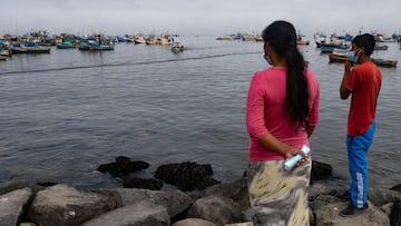 A family of artisanal fishermen observe the fishing boats moored, days after an oil spill that affected the resort town of Ancon, Peru, on January 21, 2022. - At Miramar Beach in Peru&#039;s popular resort of Ancon, there are no bathers despite the summer