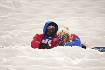 Los aficionados de los Buffalo Bills se sientan entre asientos cubiertos de nieve mientras observan a los jugadores calentar antes de un partido de fútbol americano de la NFL entre los Bills y los San Francisco 49ers en Orchard Park, Nueva York.