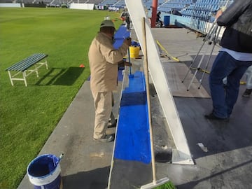 Los trabajadores pintan las bancas de color azul para recibir a la Liga MX.