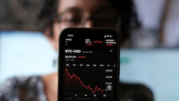 A woman shows a stock graph on her phone with the price of Bitcoin in relation to the dollar in San Salvador.