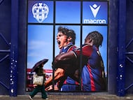 A woman walks with an umbrella outside the Ciutat de Valencia stadium after the Spanish league football match between Levante UD and Villarreal CF was suspended due to severe weather warning of torrential rains in Valencia on December 14, 2025. (Photo by Jose Jordan / AFP) PARTIDO SUSPENDIDO POR LLUVIA TEMPORAL