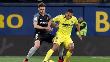 Carlos Bacca ante la marca de un rival durante el partido entre Villarreal y Sevilla por la fecha 24 de LaLiga de España.